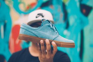 A person holding up blue suede Nike shoes