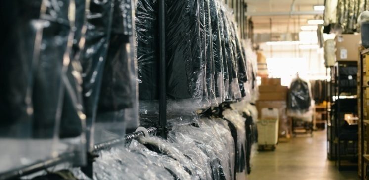 Wrapped in plastic sheets after being cleaned, black blazers are lined up on hangers to ensure they remain intact.