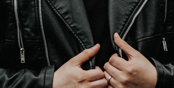 Man holding his black leather jacket with his hands
