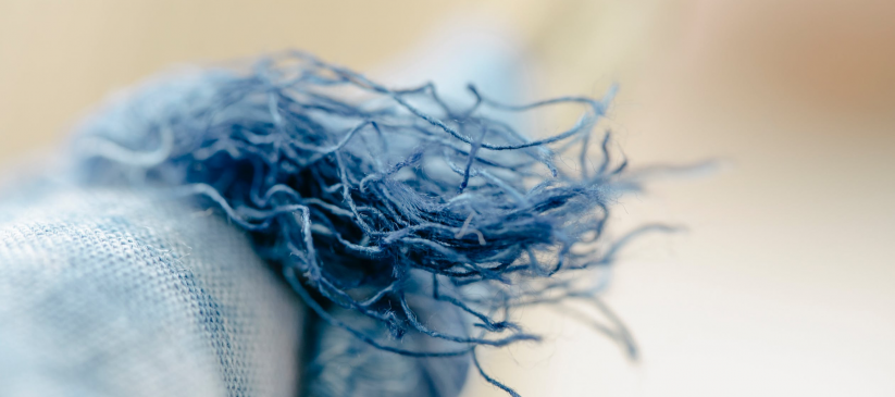 thread hanging from a blue fabric