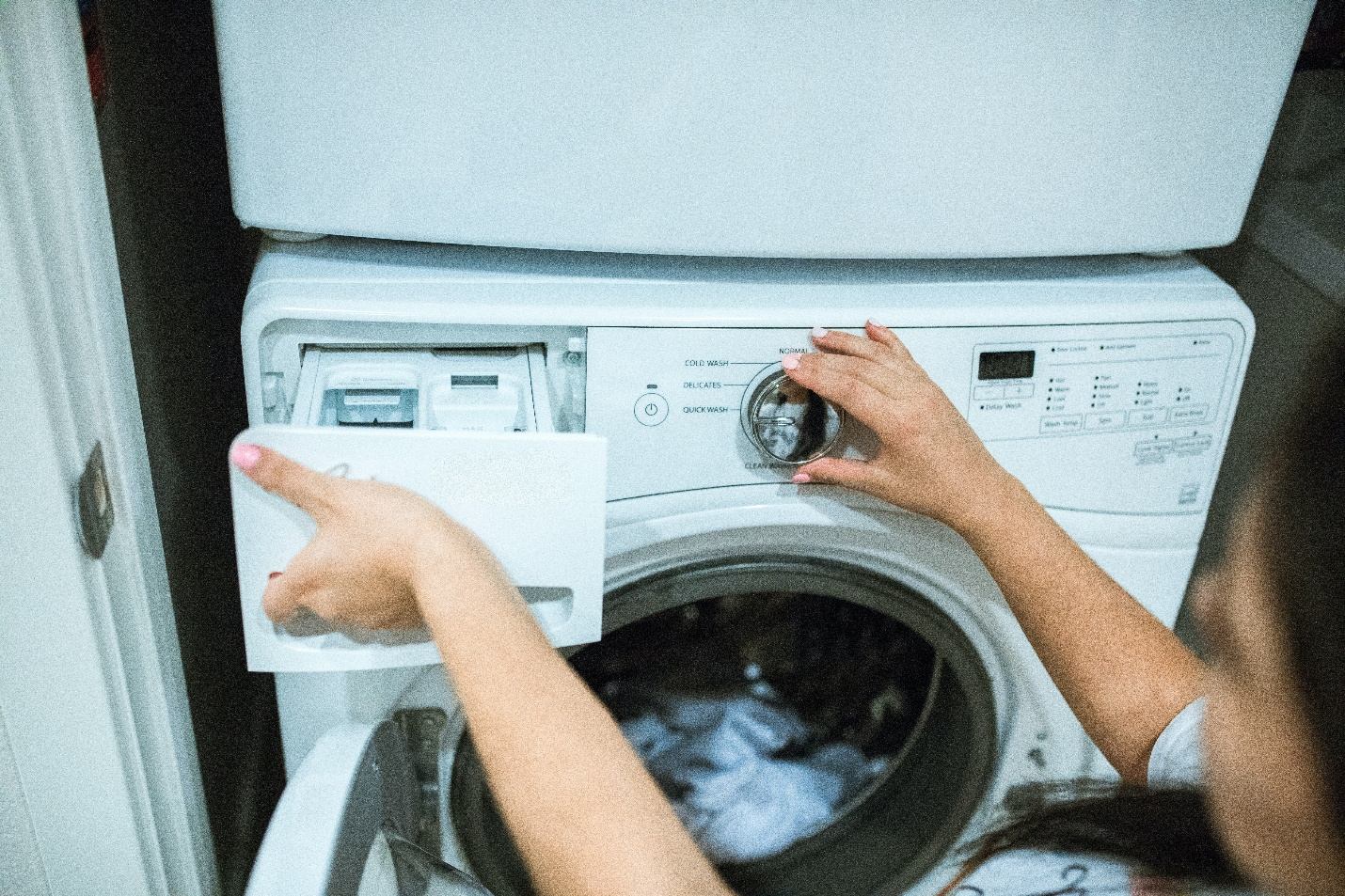 A person adding detergent and loading a washing machine