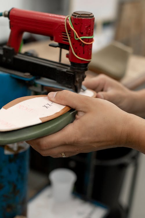 A person repairing a shoe sole using a machine