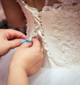 A closeup of a woman working on a perfectly fit wedding gown