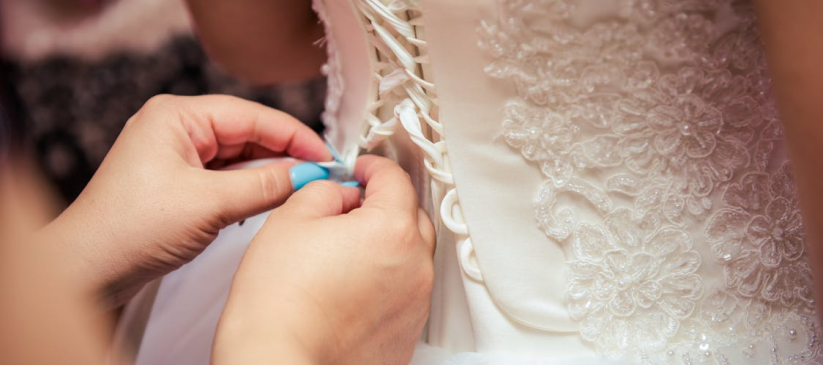 A closeup of a woman working on a perfectly fit wedding gown